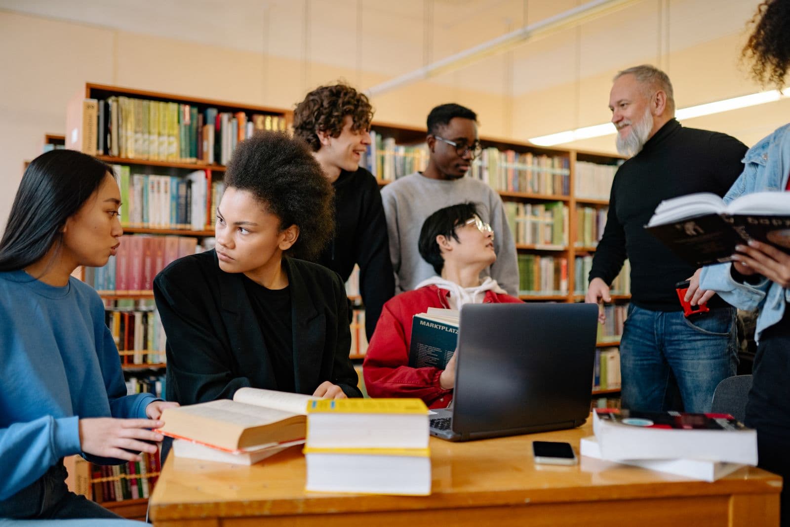 A group of students seated at a long table in a library
